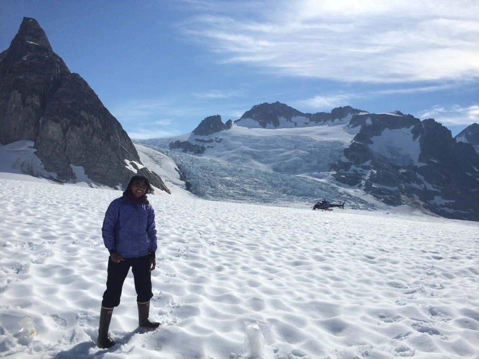 a woman stands on snow in front of mountains and glaciers
