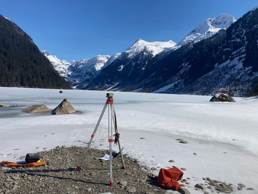 survey equipment near a frozen lake with mountains