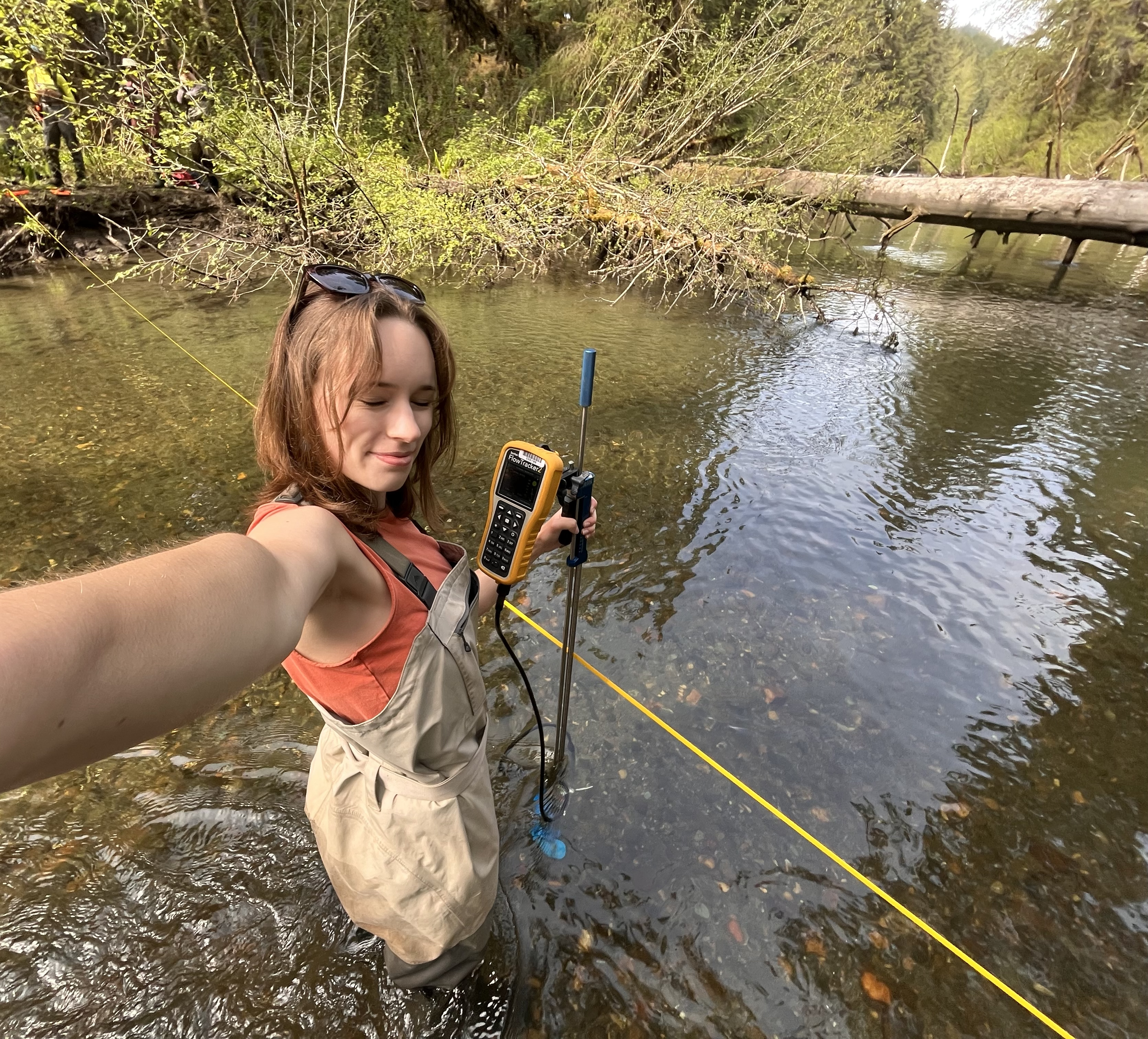 Jasmine Louwagie stands in a stream with a device to measure stream flow
