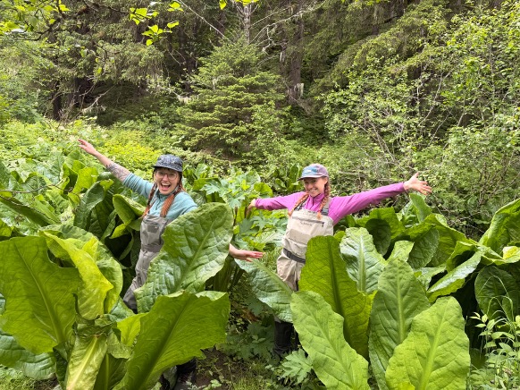 two ACRC interns in waders pose in a field of skunk cabbage