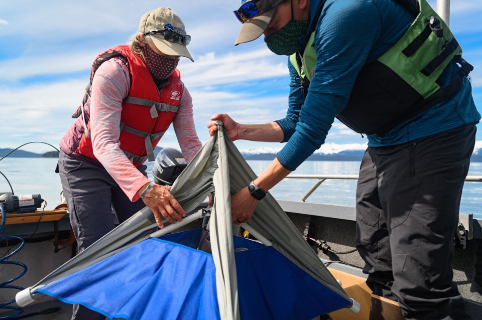 two scientists in masks assemble a piece of equipment